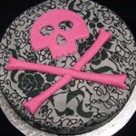 Skull and cross bones in pink rolled fondant and fancy lace detailing.